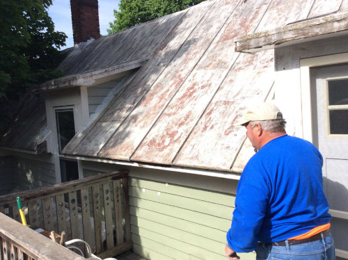 Before photo of Scott inspecting the aftermath of powerwashing the metal roof.