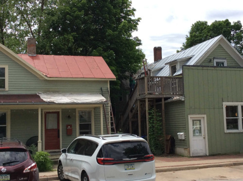 A photo of the business' roof being primed, and the rental property roof being prepped.