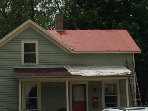 Before photo of the rental property's red metal roof.