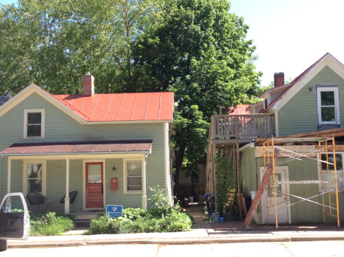 After photo of white coated roof where it connects with the red shingled interim roof.