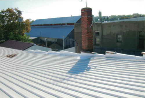 Picturesque photo of the edge of the coated roof overlooking nearby buildings.