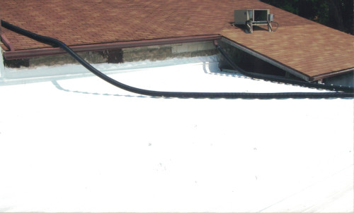 After photo of white coated roof where it connects with the red shingled interim roof.
